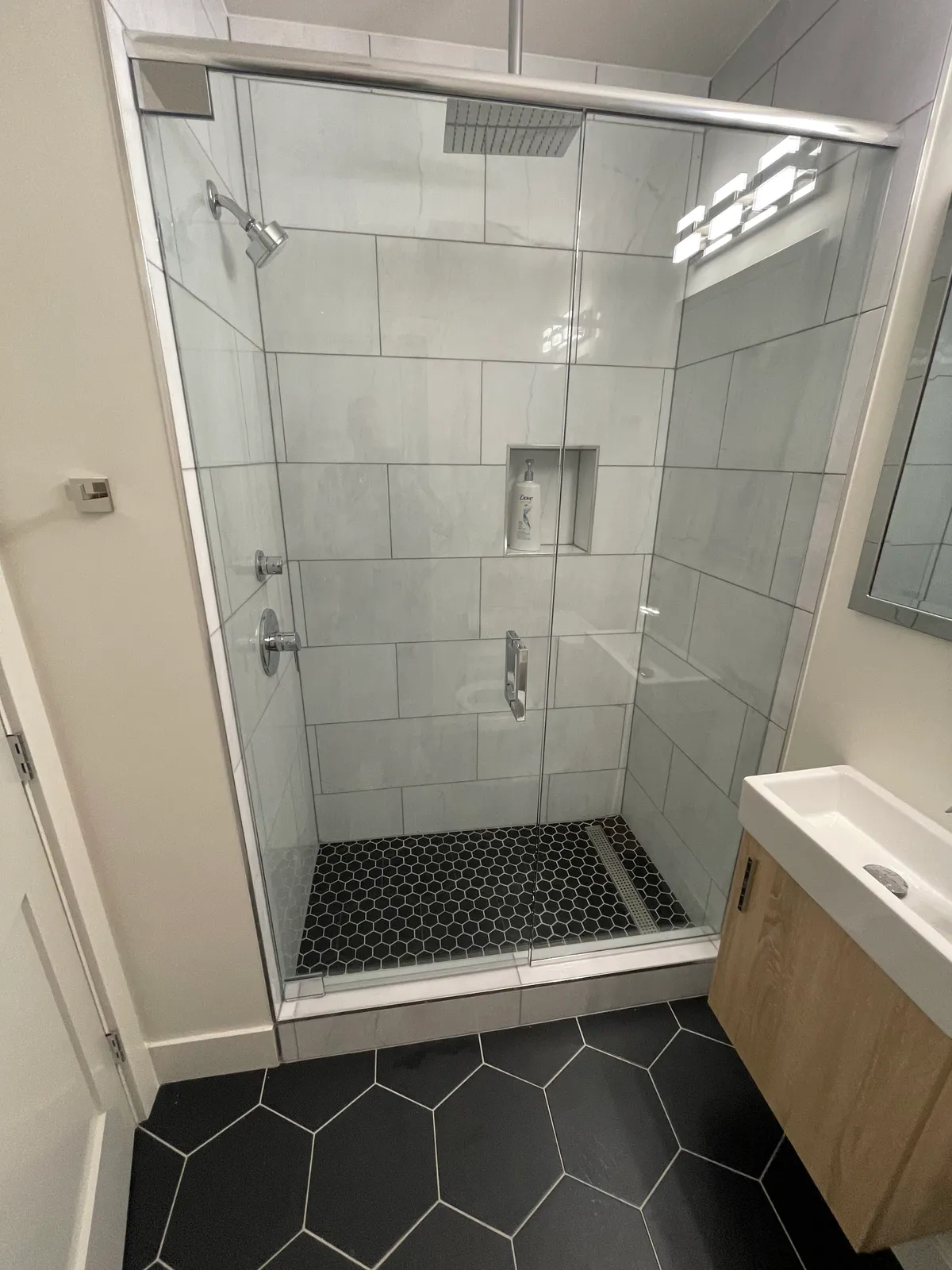 Glass shower with marble tile walls and a hexagon-tile floor